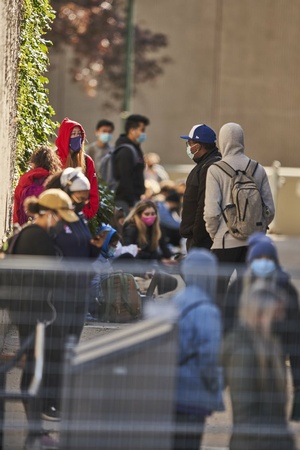 Students stand in a line on campus wearing face masks.