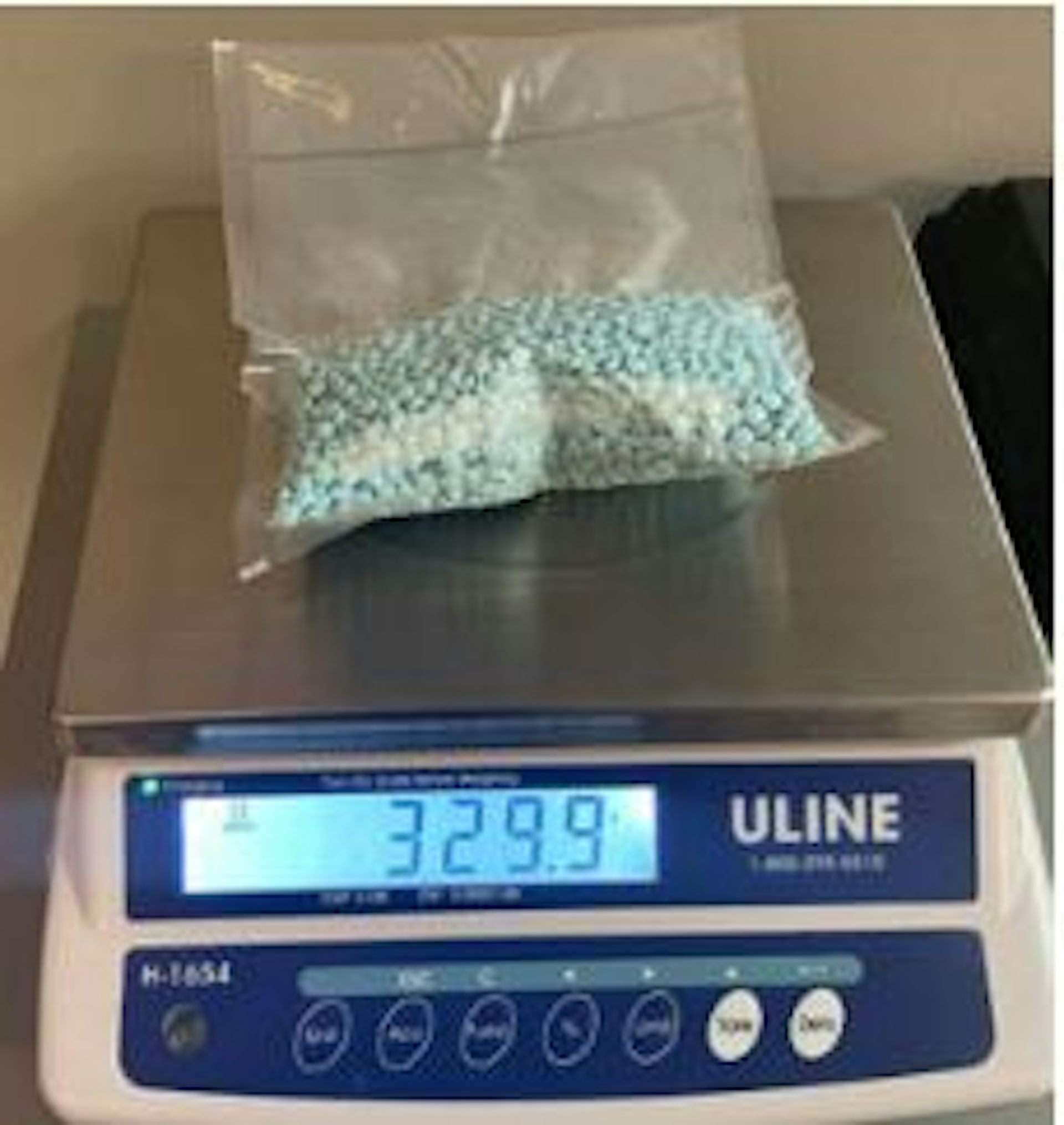 Bag containing many blue pills lying on the chrome top of a digital scale
