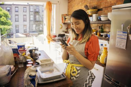 woman smiling on phone while cooking in kitchen